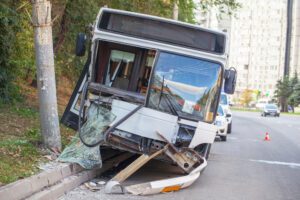 An empty, damaged bus rests on a street side curb.