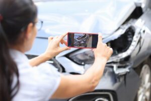 A woman using a smartphone to take photos of damage to her car as she deals with the aftermath of an accident with a Prime Inc. truck in Dayton.